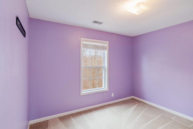 empty room with visible vents, light colored carpet, a textured ceiling, and baseboards