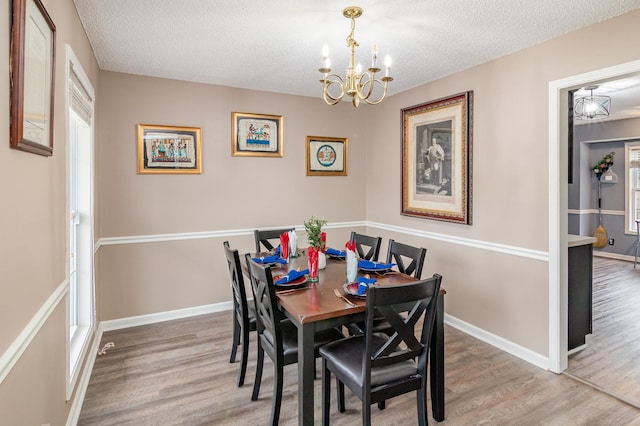 dining area featuring a textured ceiling, baseboards, and wood finished floors