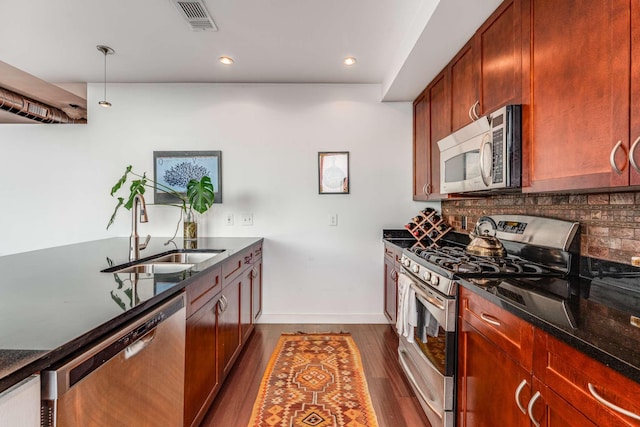 kitchen featuring dark wood-style floors, visible vents, decorative backsplash, appliances with stainless steel finishes, and a sink