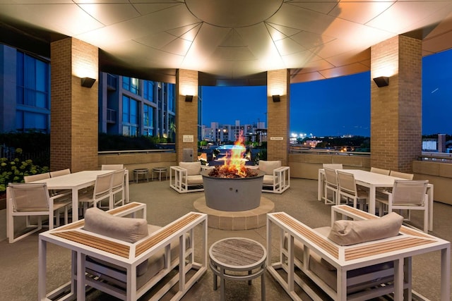 patio at twilight with a fire pit, outdoor dining area, and a view of city lights