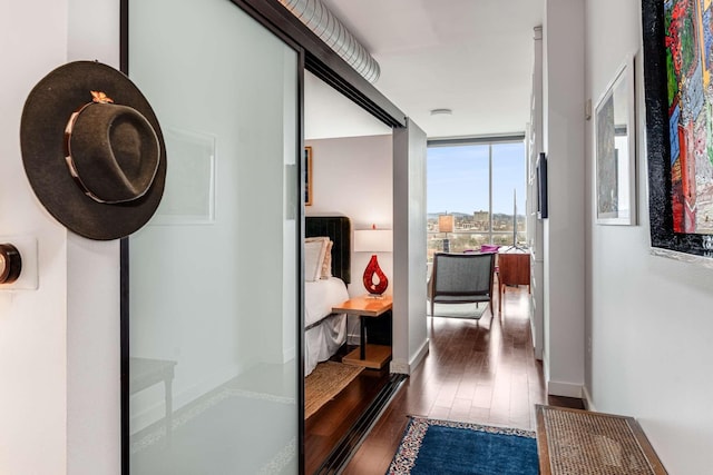 hallway featuring expansive windows, baseboards, and wood finished floors