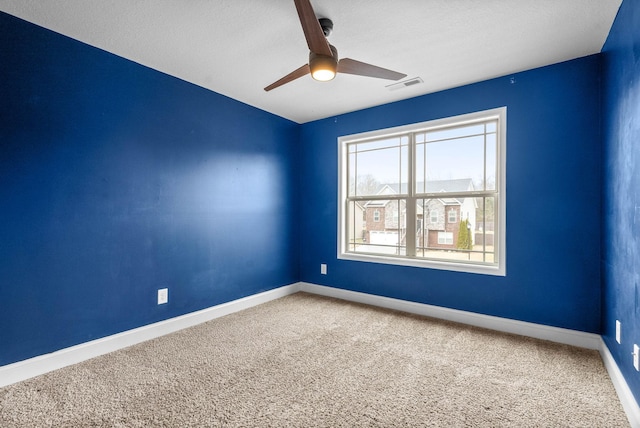 carpeted spare room with baseboards, a textured ceiling, visible vents, and a ceiling fan