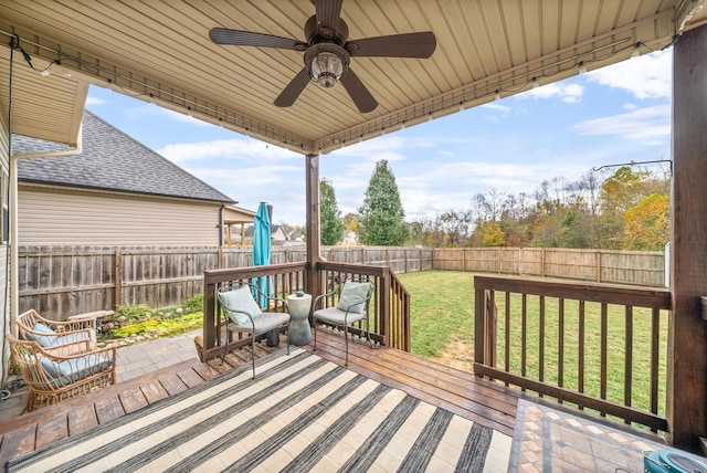 wooden terrace featuring a ceiling fan, a fenced backyard, and a lawn