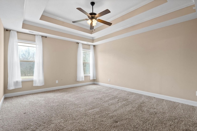 carpeted spare room with ornamental molding, a raised ceiling, and a healthy amount of sunlight