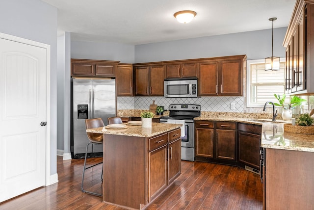 kitchen with dark wood-style floors, a center island, a breakfast bar, stainless steel appliances, and a sink