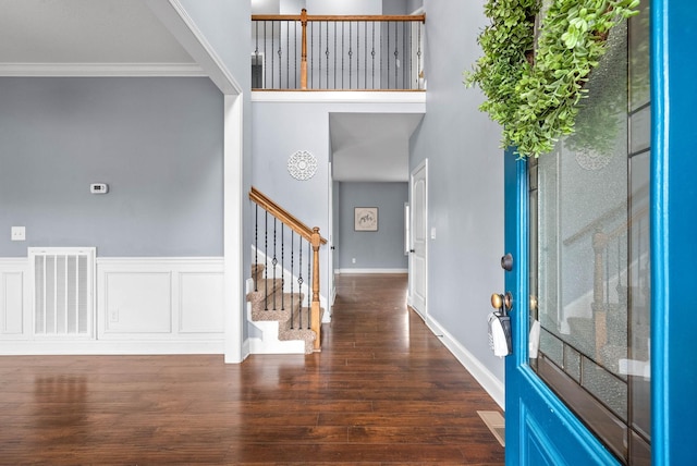 foyer entrance featuring visible vents, wainscoting, stairway, wood finished floors, and crown molding