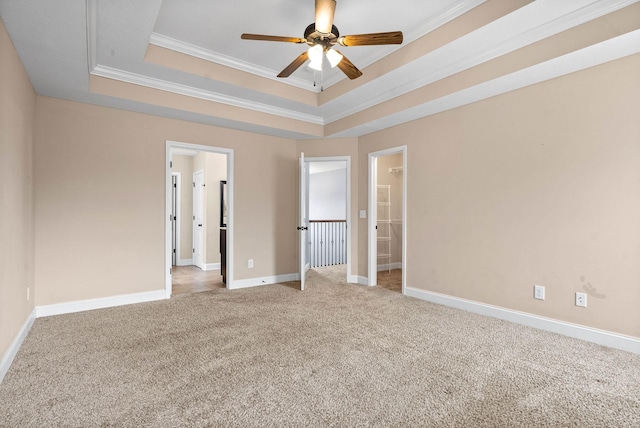 unfurnished bedroom featuring a tray ceiling, carpet, ornamental molding, connected bathroom, and baseboards