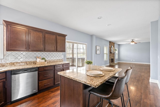 kitchen with tasteful backsplash, dark wood-style flooring, dishwasher, and light stone counters