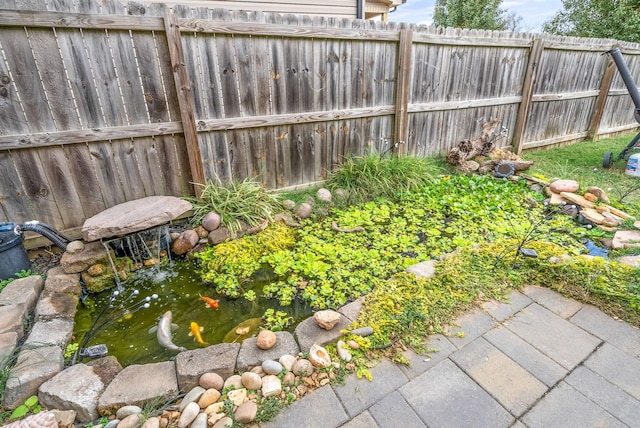 view of yard with fence and a garden pond