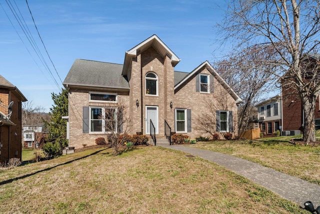 traditional-style home with a shingled roof, a front lawn, and brick siding