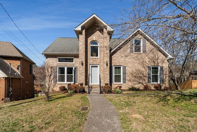 view of front of property with roof with shingles, a front lawn, and brick siding