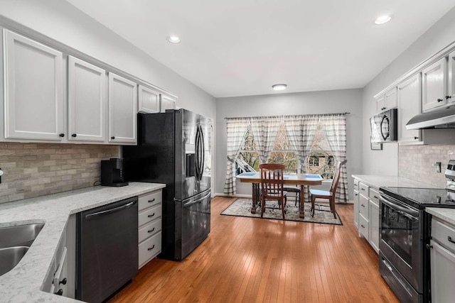 6545 Chessington Dr, Nashville, TN 37221 - kitchen featuring tasteful backsplash, appliances with stainless steel finishes, light stone countertops, under cabinet range hood, and light wood-style floors