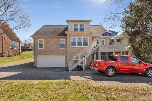 6545 Chessington Dr, Nashville, TN 37221 - view of front facade featuring a deck, aphalt driveway, an attached garage, brick siding, and stairs