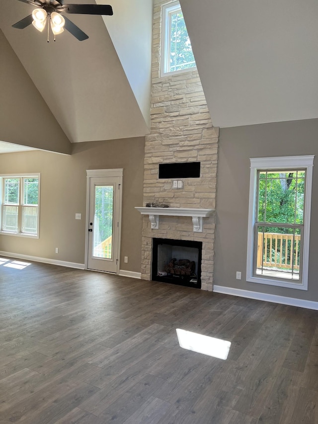 unfurnished living room featuring dark wood-style flooring, a healthy amount of sunlight, a fireplace, and baseboards