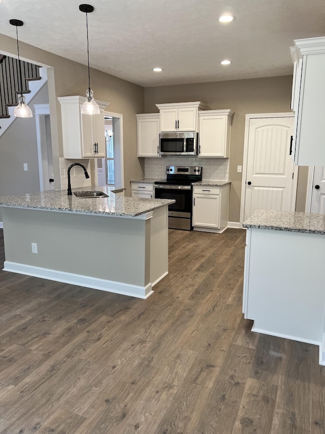 kitchen featuring appliances with stainless steel finishes, dark wood-style flooring, a peninsula, white cabinetry, and a sink