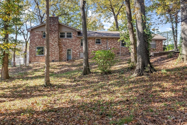 back of house with brick siding, a chimney, and fence