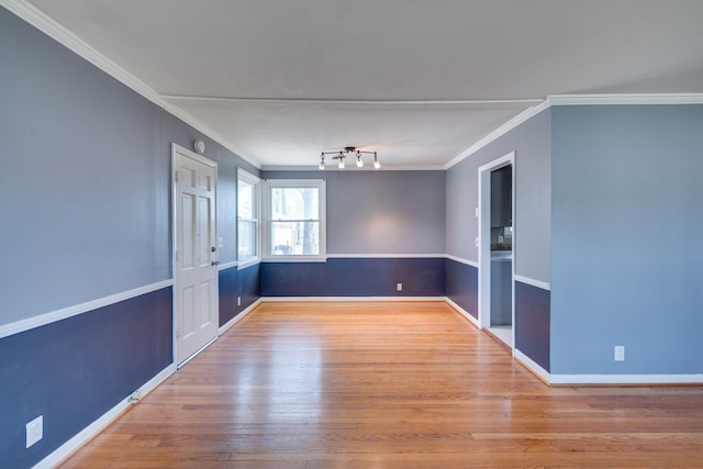 empty room with crown molding, baseboards, and wood finished floors