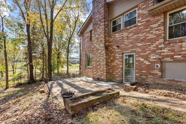 back of property featuring brick siding, a patio, and a chimney