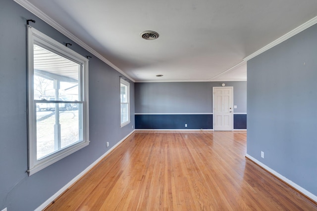 empty room featuring ornamental molding, light wood-style flooring, visible vents, and baseboards