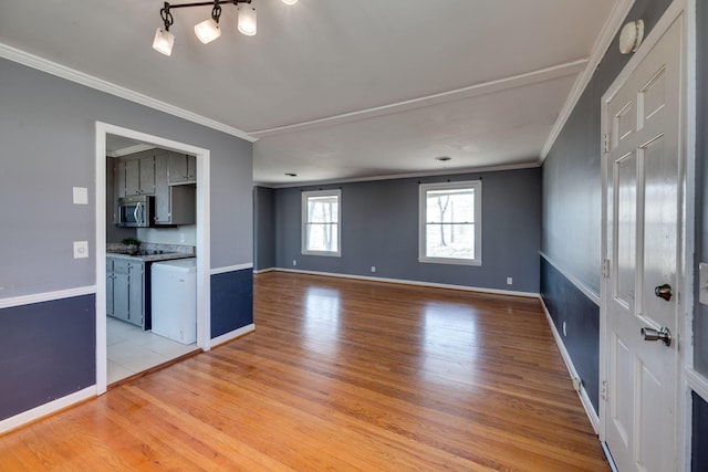 unfurnished living room with ornamental molding, light wood-type flooring, and baseboards