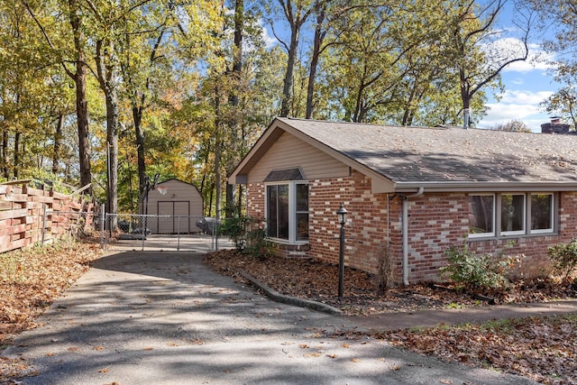 view of home's exterior featuring a garage, a chimney, an outbuilding, fence, and brick siding