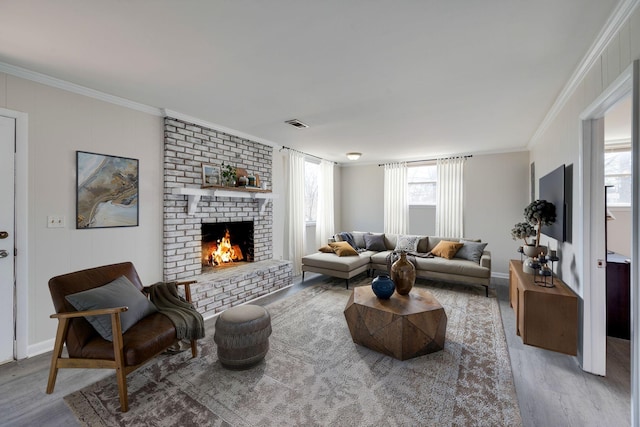 living room featuring ornamental molding, a brick fireplace, wood finished floors, and visible vents