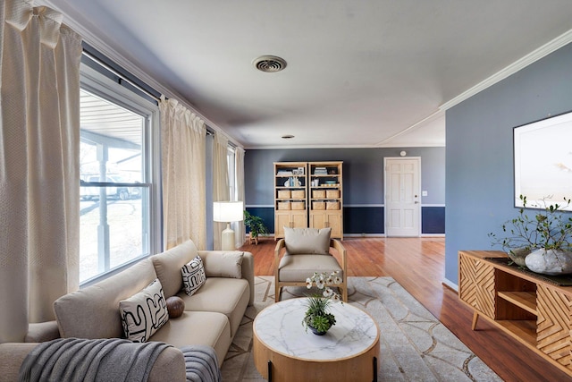 living area featuring visible vents, crown molding, and wood finished floors