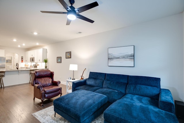 living room featuring arched walkways, recessed lighting, wood finished floors, visible vents, and baseboards