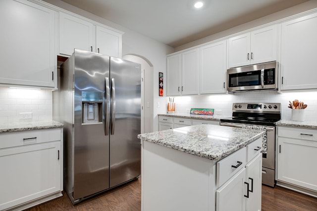 kitchen featuring appliances with stainless steel finishes, white cabinets, decorative backsplash, and dark wood-style floors