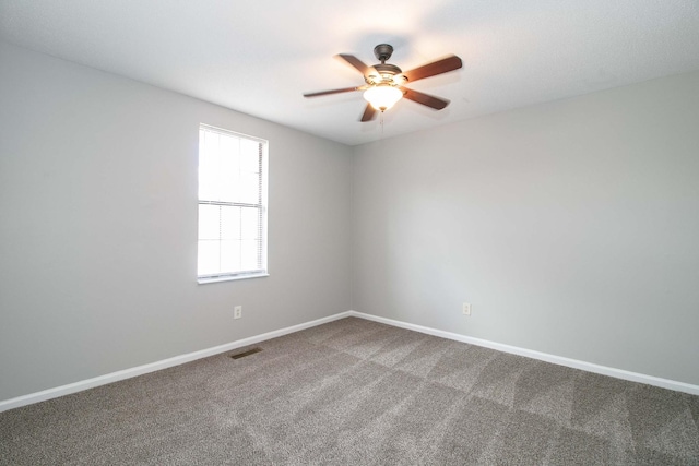 carpeted spare room featuring visible vents, ceiling fan, and baseboards