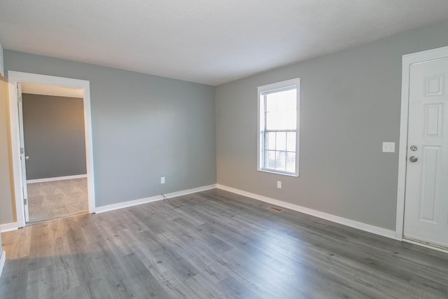 spare room featuring visible vents, baseboards, and wood finished floors