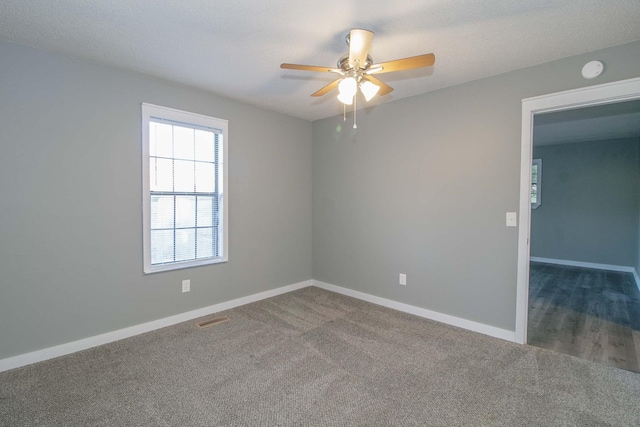 spare room featuring carpet floors, visible vents, ceiling fan, and baseboards