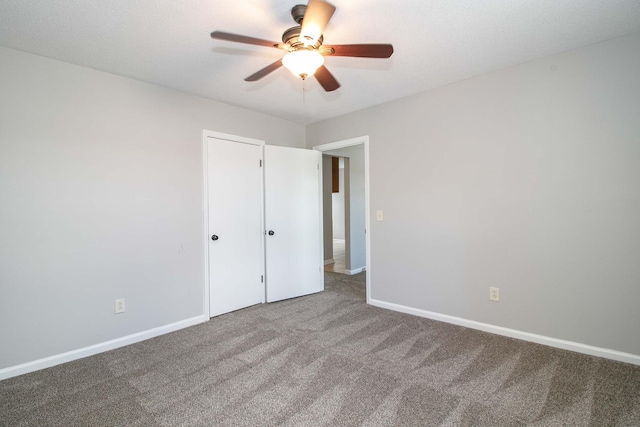 unfurnished bedroom with carpet, a ceiling fan, and baseboards