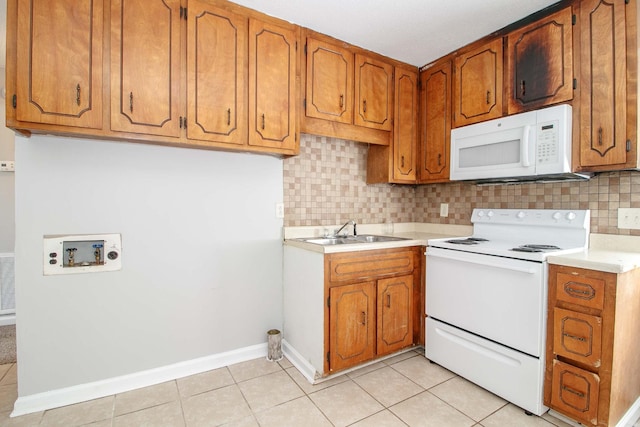 kitchen with white appliances, light tile patterned floors, brown cabinets, and a sink