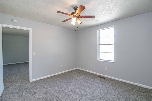 spare room with carpet floors, visible vents, ceiling fan, and a textured ceiling