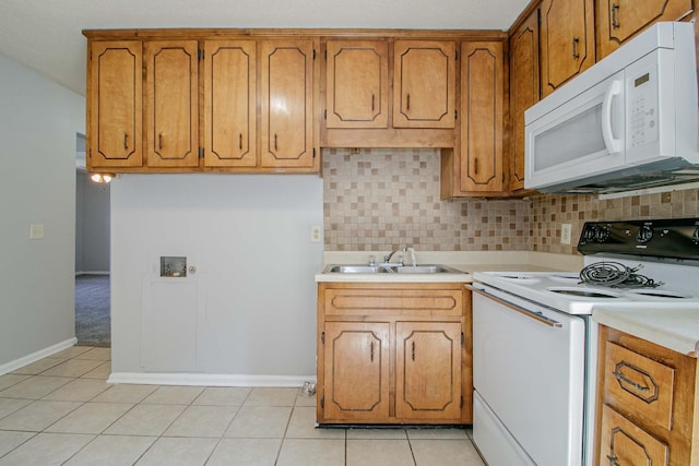 kitchen with electric range, white microwave, brown cabinets, light countertops, and a sink