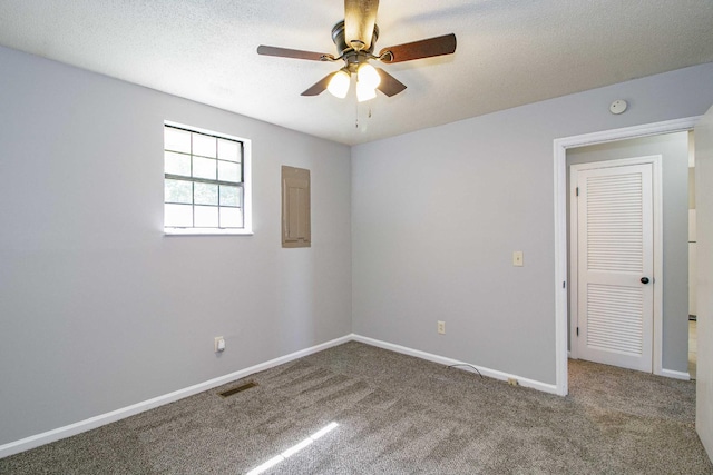 carpeted spare room with visible vents, a ceiling fan, a textured ceiling, electric panel, and baseboards