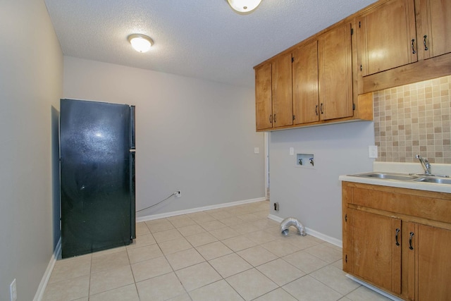 laundry area featuring washer hookup, light tile patterned floors, cabinet space, a sink, and baseboards