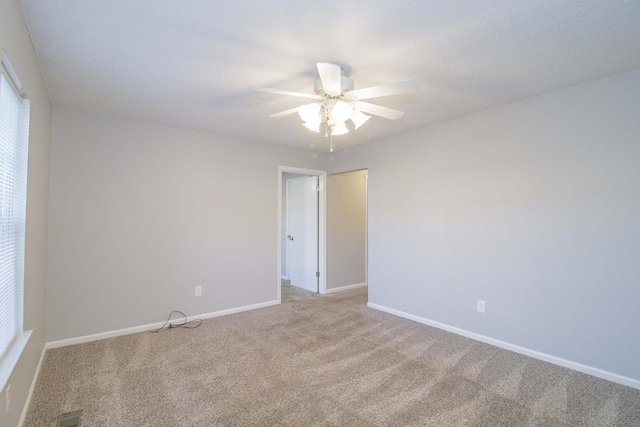 spare room with a textured ceiling, carpet floors, a ceiling fan, and baseboards