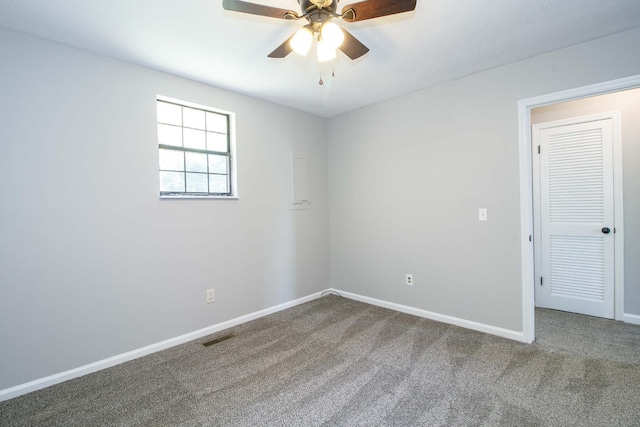 carpeted spare room with visible vents, a ceiling fan, and baseboards