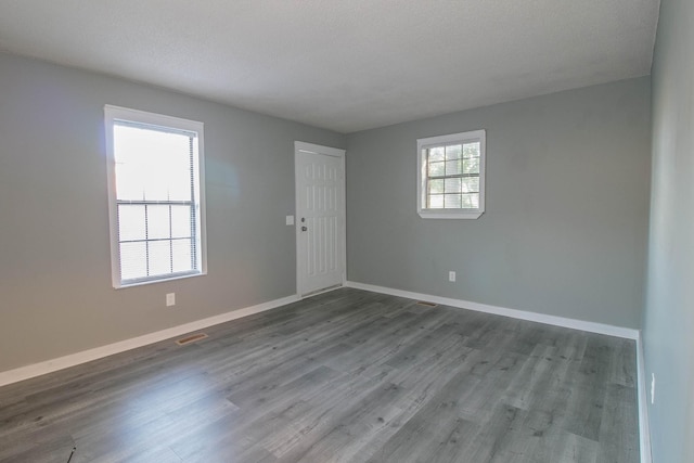 spare room with visible vents, a textured ceiling, baseboards, and wood finished floors