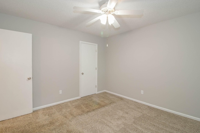 empty room featuring a textured ceiling, carpet floors, a ceiling fan, and baseboards