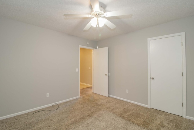 unfurnished room featuring a ceiling fan, carpet, baseboards, and a textured ceiling