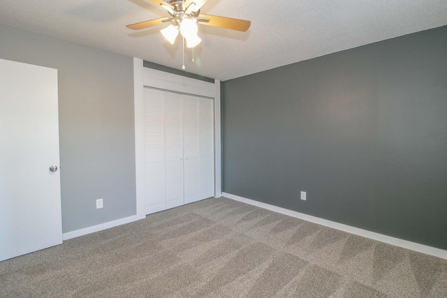 unfurnished bedroom with carpet, a textured ceiling, baseboards, and a closet