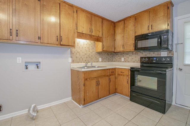 kitchen featuring light tile patterned floors, decorative backsplash, light countertops, black appliances, and a sink