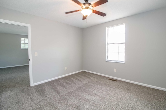 carpeted empty room featuring visible vents, ceiling fan, and baseboards