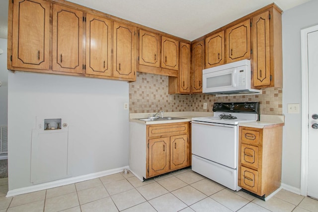 kitchen featuring tasteful backsplash, white appliances, a sink, and brown cabinets