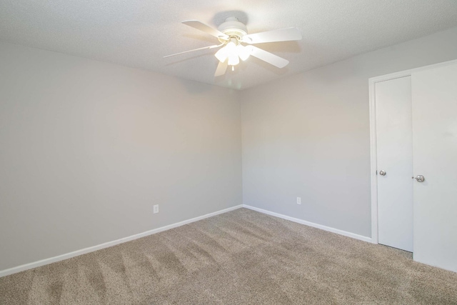 carpeted spare room featuring a textured ceiling, baseboards, and a ceiling fan