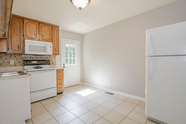 kitchen with light tile patterned floors, light countertops, visible vents, backsplash, and white appliances