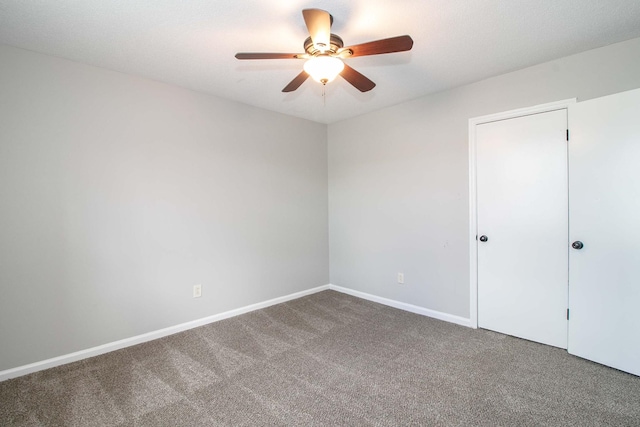 carpeted empty room with ceiling fan and baseboards